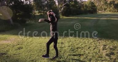 小男孩戴着自制的忍者面具，穿着黑色服装，在公园里练习忍者动作、忍者、转身和踢到一边